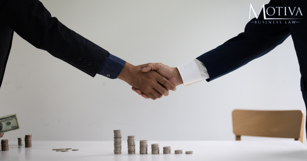 Why Do You Need A Lawyer In A Merger And Acquisition? - 2 lawyers shaking hands over a table with money